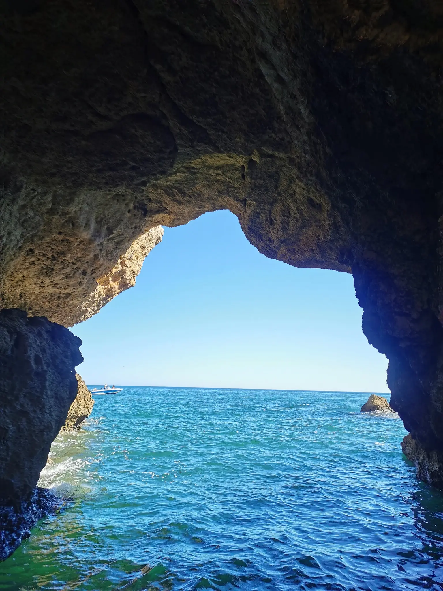 Boca de gruta a enquadrar o mar azul e o céu