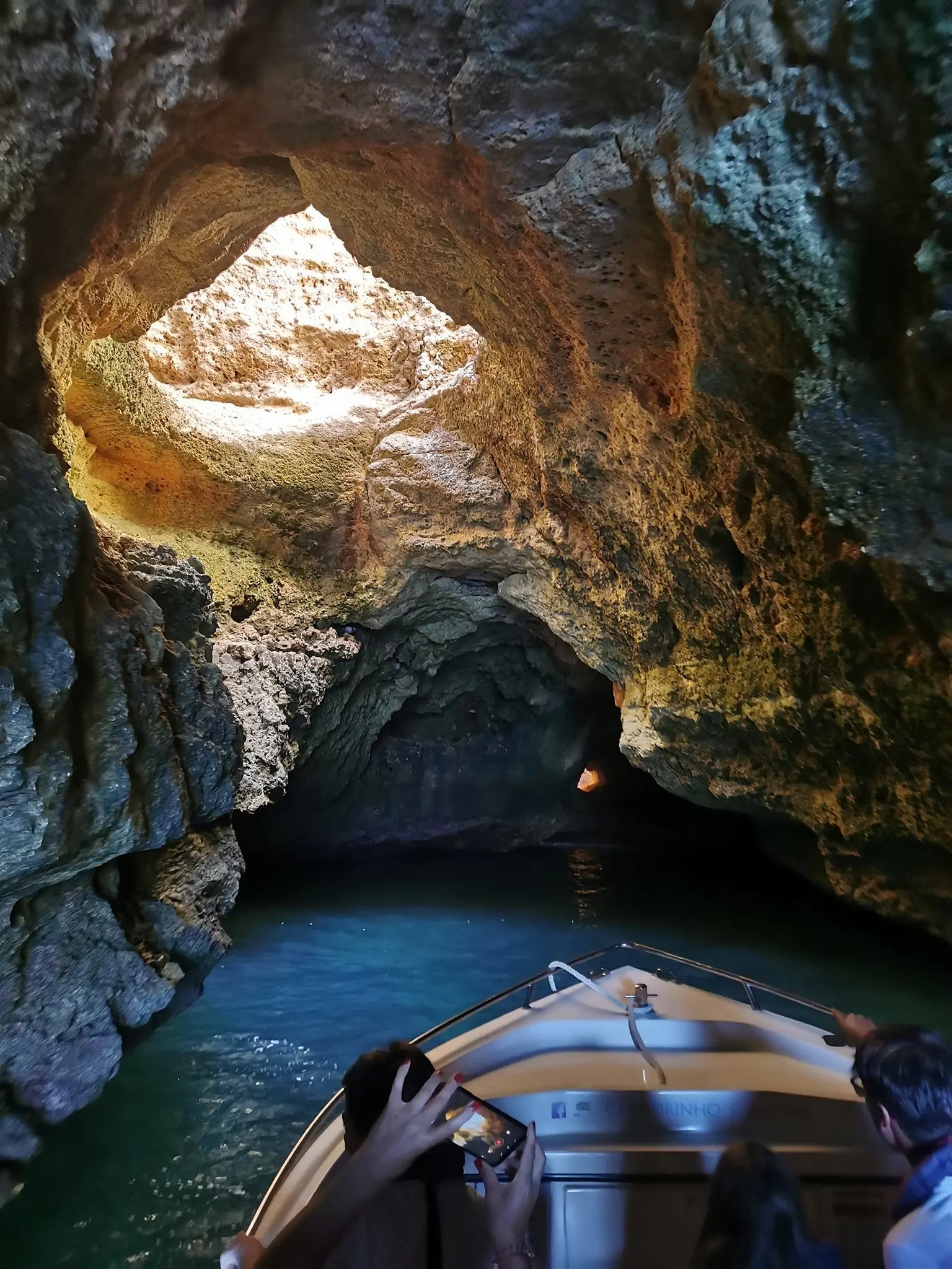 Proa do barco a entrar numa gruta iluminada