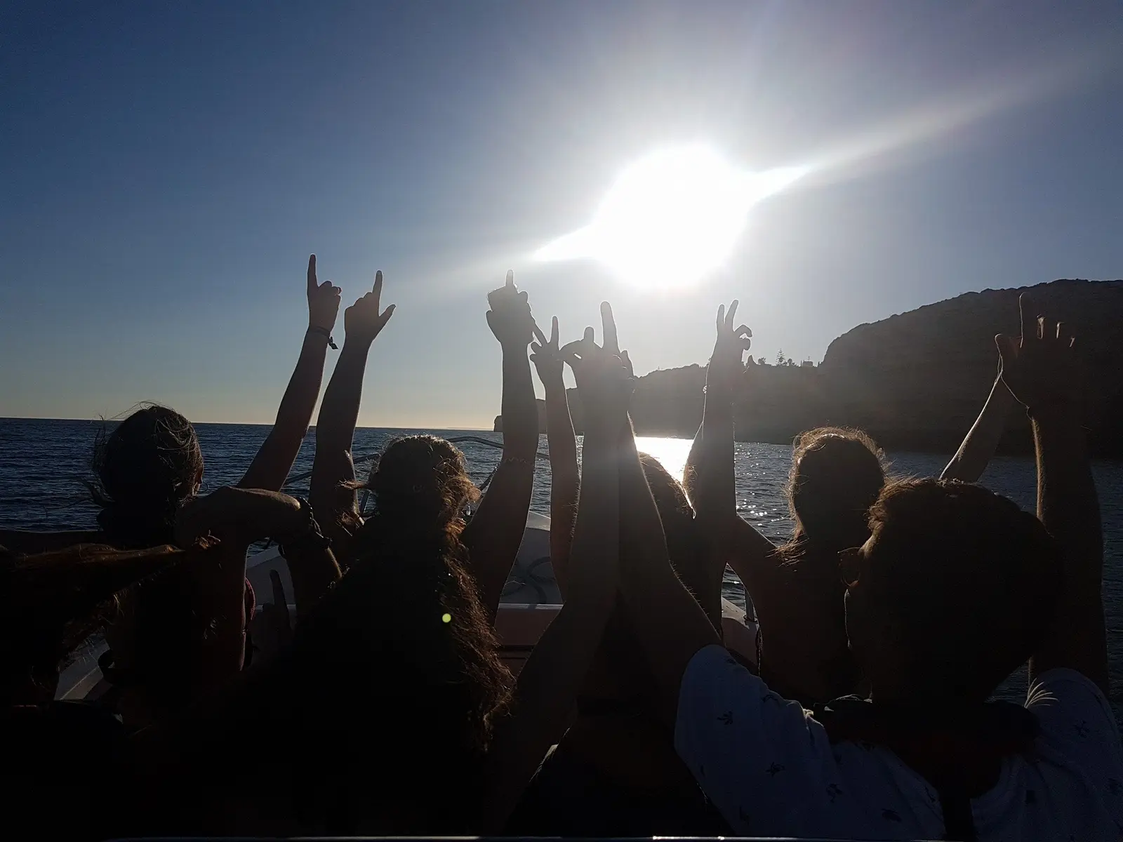 Mãos erguidas na proa, contra o sol