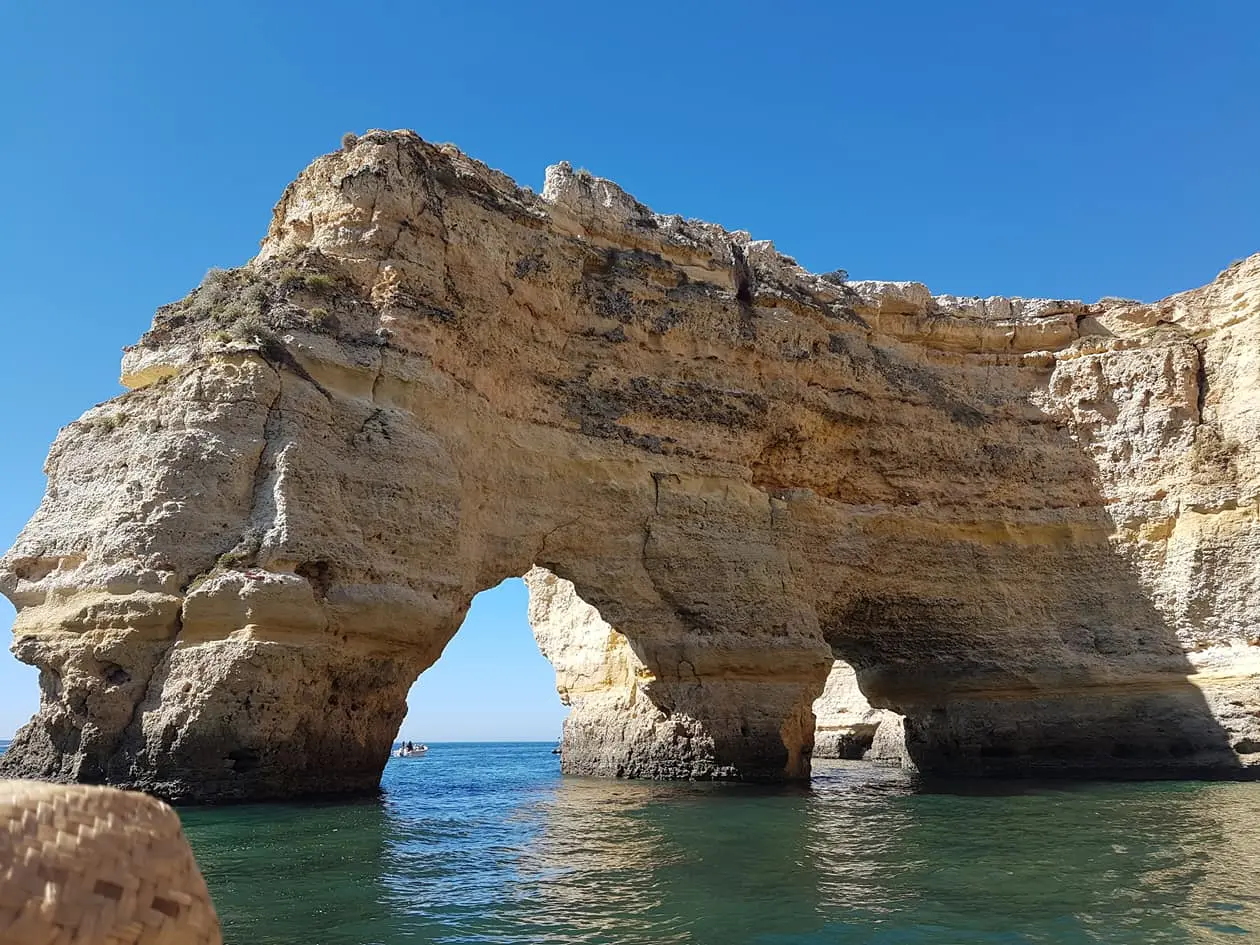 Arco duplo de rocha na Praia da Marinha, com céu azul