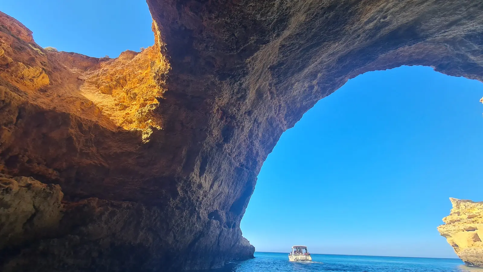 Grande arco de rocha junto a Benagil, com o mar e o céu
