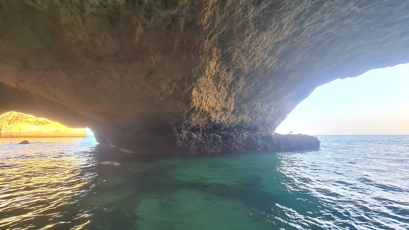 Por baixo de um arco, água verde e a arriba ao sol